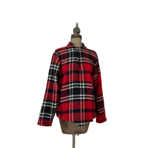 May include: Red and black plaid flannel shirt with a single button closure. The shirt is long-sleeved and has a relaxed fit.