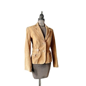 May include: A tan suede blazer with a double breasted closure and a belt at the waist.