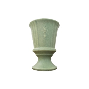 May include: A green ceramic planter with a fluted design and a diamond pattern. The planter has a pedestal base.