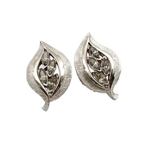 May include: A pair of silver tone leaf-shaped earrings with clear rhinestone accents.