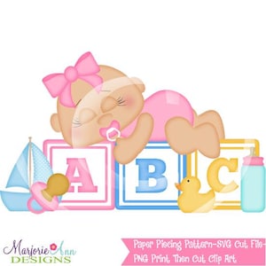 May include: A cartoon illustration of a baby with a pink bow, pacifier, and outfit, resting on ABC blocks. A sailboat, duck, and bottle are also featured. The design includes the text "Marjorie Ann Designs" and "Paper Piecing Pattern-SVG Cut File".