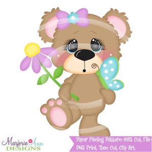 Op de afbeelding: Illustratie van een bruine teddybeer met een roze strik, die een paarse bloem en een blauwe vlinder vasthoudt. De beer heeft grote ogen en roze accenten. Tekst onderaan luidt "Marjorie Ann Designs" en "Paper Piecing Pattern-SVG Cut File-PNG Print Then Cut, Clip Art."