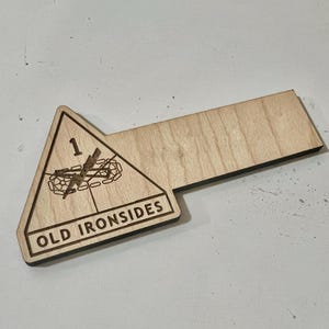Puede incluir: Llavero de madera con forma triangular y el texto "OLD IRONSIDES" y el número "1" en él.