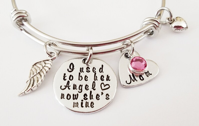 May include: Silver charm bracelet with a heart charm that says "Mom" with a pink rhinestone, a wing charm, and a round charm that says "I used to be her Angel now she's mine".