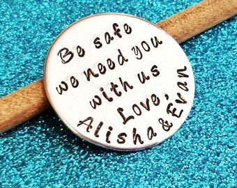 May include: Silver round charm with the text "Be safe we need you with us Love, Alisha & Evan"