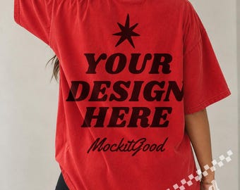 Puede incluir: Una camiseta roja de manga corta con un icono de estrella negra sobre el texto negro en negrita "YOUR DESIGN HERE" y la escritura cursiva "MockitGood" impresa en la espalda. La camiseta tiene un corte relajado y una textura de tela ligeramente desgastada.
