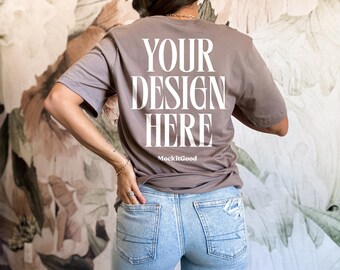 May include: A brown t-shirt with the text "YOUR DESIGN HERE" and the words "MockitGood" printed on the back. The t-shirt is being worn by a person with blue jeans.