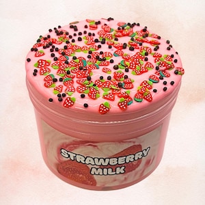 Peut inclure: Un pot de slime rose, décoré de fraises et de garnitures noires en forme de vermicelles. Le récipient porte l'inscription "Strawberry Milk". Le slime a un aspect brillant.