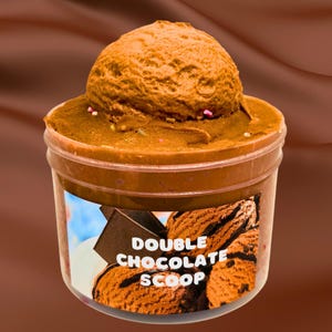 May include: A clear plastic container filled with a brown chocolate slime with a chocolate ice cream scoop on top. The container has a label that says "Double Chocolate Scoop".