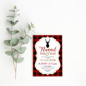K&ouml;nnte beinhalten: Eine rechteckige Einladung mit einem rot-schwarzen Karomuster. Die Einladung zeigt den Text "Flannel Fur & Fizz" in Rot und Gold, zusammen mit Veranstaltungsdetails und einer Hirschsilhouette. Eukalyptuszweige befinden sich links.