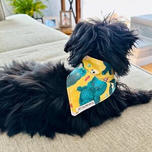 May include: A black dog wearing a yellow bandana with a blue and green cupie doll Swamp Thing monster print.