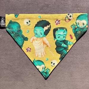 May include: A yellow triangle shaped dog bandana with a green, blue, and white cupie doll Bride of Frankenstein and Frankenstein, Swamp Thoing and Wolf Man