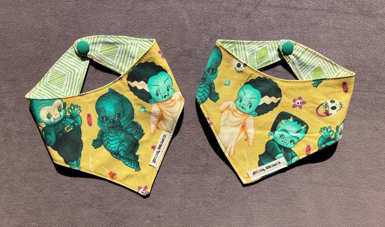 May include: Two yellow fabric bandanas with green, white, and black monster and skull illustrations. The bandanas have a green and white geometric pattern on the reverse side.