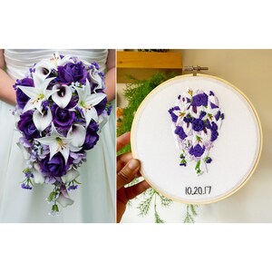 May include: A white embroidery hoop with a purple and white floral design embroidered inside. The date 10.20.17 is embroidered at the bottom of the hoop.