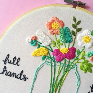 Puede incluir: Arte de bordado en aro con un tarro de cristal lleno de flores de colores. El texto "full hands" est&aacute; bordado en hilo negro debajo del tarro.