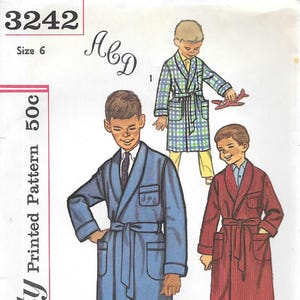 May include: A Simplicity sewing pattern envelope 3242 for size 6, featuring illustrations of three robes. One is solid blue, one is a blue and green plaid, and one is solid red. Each robe has a shawl collar, a tie belt, and two front pockets.