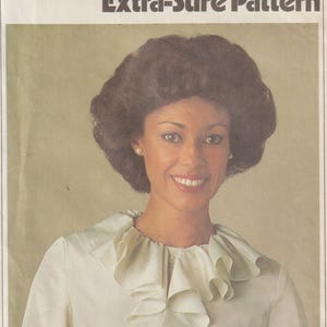 May include: A vintage Simplicity 8187 sewing pattern envelope featuring a photograph of a person wearing a long-sleeved, off-white blouse with a prominent ruffled collar. The text on the envelope reads 8187, Simplicity, E.S.P, Extra-Sure Pattern, and SIZE R.