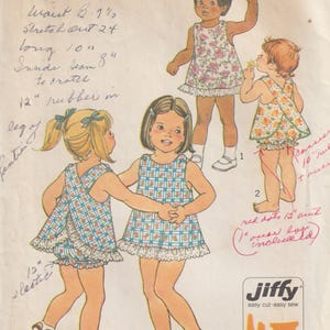 Op de afbeelding: Een Simplicity 7407 naaipatroon-envelop voor kinderkleding, met illustraties van kinderen in bloemrijke en geruite jurkjes met bijpassende pofbroekjes. De gele papieren hoes bevat handgeschreven notities en de merknaam Jiffy.