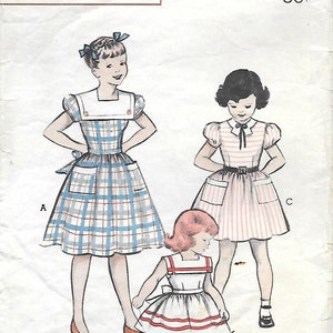 Puede incluir: Patrón impreso Butterick vintage para vestidos de niña. La ilustración muestra tres diseños de vestidos diferentes: un vestido a cuadros, un vestido a rayas y un vestido blanco con detalles rojos. El patrón incluye información de tallas y el logotipo de Butterick.