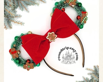 May include: Red velvet bow with a gingerbread star charm, attached to a headband with two green Christmas wreaths decorated with gingerbread men and ornaments. The headband has a black and white logo that says "roundtrip.etsy.com" with a castle graphic.
