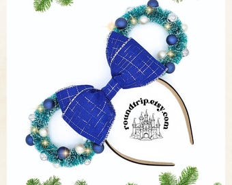 May include: Blue and white plaid bow with a blue and green Christmas wreath on each side. The headband is brown and has the text "roundtrip.etsy.com" with a castle graphic.