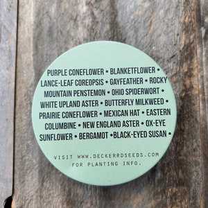 May include: A green circle with a list of flower names, including Purple Coneflower, Blanketflower, Lance-Leaf Coreopsis, Gayfeather, Rocky Mountain Penstemon, Ohio Spiderwort, White Upland Aster, Butterfly Milkweed, Prairie Coneflower, Mexican Hat, Eastern Columbine, New England Aster, Ox-Eye Sunflower, Bergamot, and Black-Eyed Susan. The text also includes the website address "www.deckerrdseeds.com" and the phrase "For Planting Info."