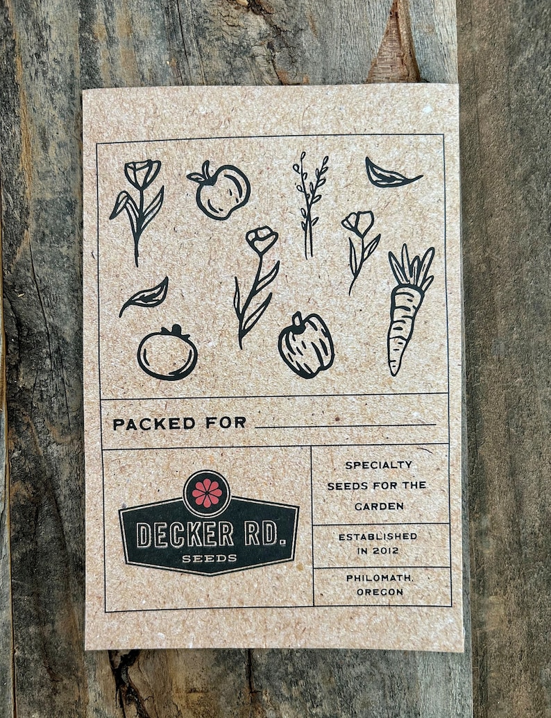 May include: A brown paper card with black illustrations of various garden plants and vegetables. The card has the text "PACKED FOR" at the top and a logo for "DECKER RD. SEEDS" in the center. The text "SPECIALTY SEEDS FOR THE GARDEN" is in the top right corner. The text "ESTABLISHED IN 2012 PHILOMATH, OREGON" is in the bottom right corner.