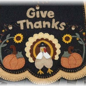 May include: A felt Thanksgiving door hanging with a turkey, pumpkins, sunflowers, and the text "Give Thanks".