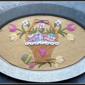 May include: A felt Easter table runner with a basket of colorful eggs, surrounded by tulips and flowers. The runner is displayed on a silver oval tray.