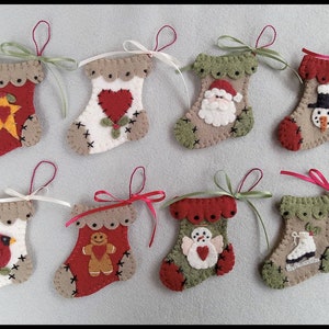 May include: Nine felt Christmas stockings with different designs, including a cardinal, gingerbread man, snowman, Santa Claus, and a star. The stockings are all red, green, and white with brown trim.