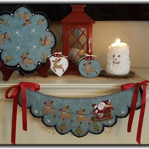 May include: A blue felt Christmas garland with a scalloped edge and red ribbon ties. The garland features a Santa Claus in a red sleigh pulled by reindeer. There are also smaller blue felt ornaments with reindeer designs.