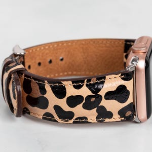 May include: A brown leather watch strap with a leopard print design. The strap is compatible with Apple Watch.