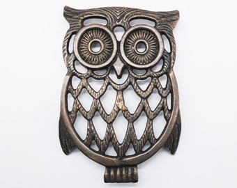 May include: A bronze metal owl ornament with a cut-out design. The owl has large, round eyes and a detailed feather pattern.