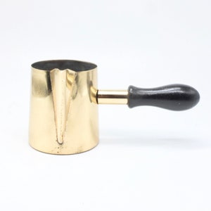 Op de afbeelding: Een gouden metalen koffiepot met een zwart houten handvat. De pot heeft een rond lichaam en een tuit aan de ene kant.