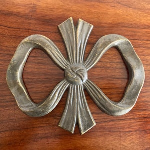 以下が含まれることがあります： テクスチャ加工が施され、エイジング加工された装飾的な金属製の弓。弓は1つの金属片でできており、3次元のデザインになっています。