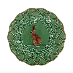 Puede incluir: Un plato decorativo de cerámica verde con un conejo marrón en el centro. El plato presenta un diseño detallado de vides y un borde festoneado. El plato tiene aproximadamente 25 cm de diámetro.