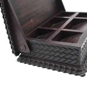 May include: A dark brown wooden box with a hinged lid and a carved design. The box has six compartments inside.
