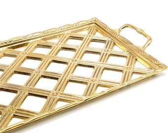 May include: A rectangular gold-toned metal serving tray featuring an open lattice grid pattern. The tray has a raised border with a decorative scalloped edge and two integrated handles on the short sides, showcasing a polished finish.