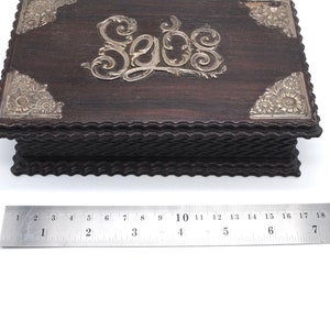 May include: A dark wood box with silver accents and the word "Sobs" engraved on the top. The box has a decorative, scalloped edge.