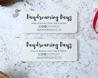 May include: Two white business cards with the text "Daydreaming Dayz" in black script font. The text "Bespoke Business Cards, Tags & Stickers" is printed below the business name. Social media icons for Instagram, Twitter, and Facebook are included with the text "DAYDREAMINGDAYZ". The website address "WWW.DAYDREAMINGDAYZ.ETSY.COM" is printed below the social media icons.