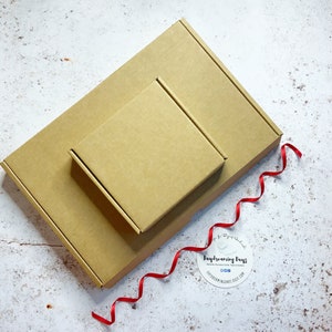 May include: Two brown cardboard boxes, one nested inside the other, with a red ribbon and a round sticker that says "Daydreaming Days".