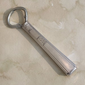 May include: A silver bottle opener with a decorative design on the handle.