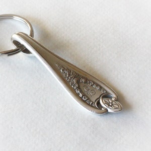 May include: Silver spoon keychain with a decorative design and the initials "C.S." engraved on the handle.