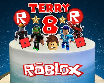 May include: A blue and white cake decorated with a red and white Roblox logo, red 'R's, a red number 8, two gold stars, and five Roblox character figurines. The cake is decorated with the name 'TERRY' in black letters.