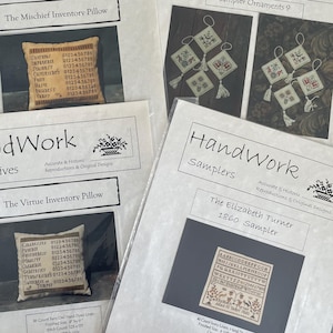 May include: Four printed patterns from HandWork, featuring cross-stitch designs. The patterns include samplers and inventory pillows with text and images. The designs are in black and white.