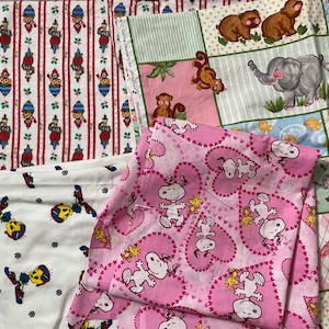 May include: Assortment of fabric scraps featuring various patterns, including a pink fabric with a repeating pattern of Snoopy and Woodstock, a white fabric with a repeating pattern of Tweety Bird, a red and white fabric with a repeating pattern of a Christmas ornament, and a multi-colored fabric with a repeating pattern of animals.
