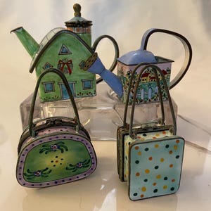 May include: Four miniature enamelware items: a green house-shaped teapot, a blue watering can, a green and purple purse with floral designs, and a blue purse with yellow and green polka dots.