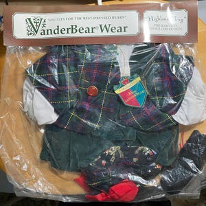 May include: A VanderBear Wear Scottish dance costume set in a clear plastic package. The outfit includes a green and plaid vest, skirt, and accessories. The packaging includes the text "Highland Fling" and "Outfits for the Best-Dressed Bears."