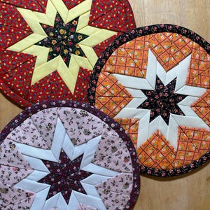 May include: A white ceramic mug with a black handle and the text "But First, Coffee" in a bold, black font. The mug is set against a blurred background, suggesting a cozy setting.