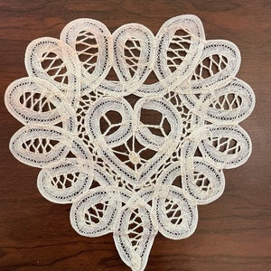 May include: A white crocheted heart-shaped doily with intricate patterns.